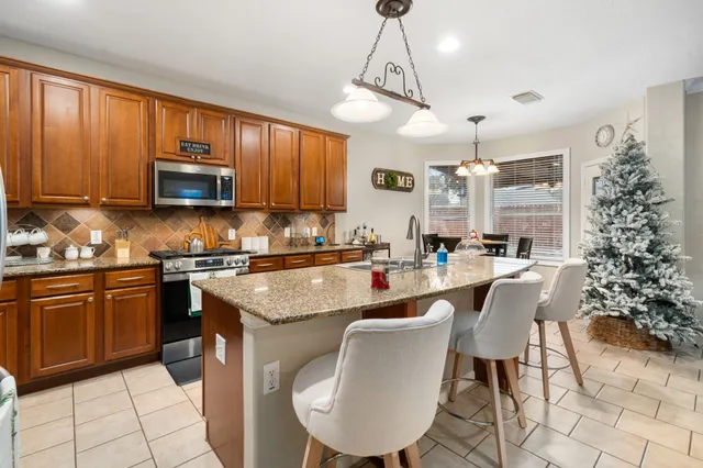 a kitchen with granite countertop a stove a sink a dining table and chairs