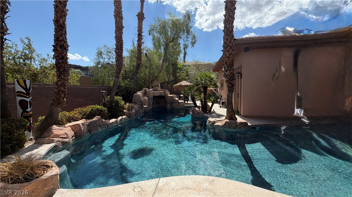 490 Toucan Ridge Court Henderson, NV 89012 - Photo 5 of 7 Mature palms frame a sparkling backyard swimming pool complete with custom stone waterfall detailing.