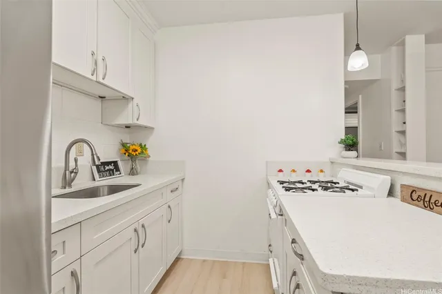 a kitchen with stainless steel appliances a white stove top oven a sink dishwasher and white cabinets with wooden floor