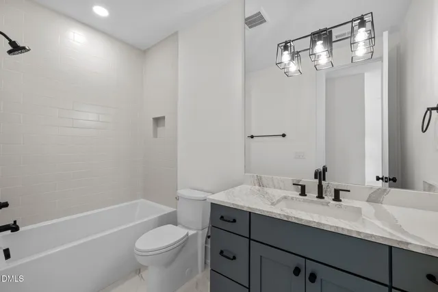 a bathroom with a granite countertop sink a toilet a mirror a bathtub and shower