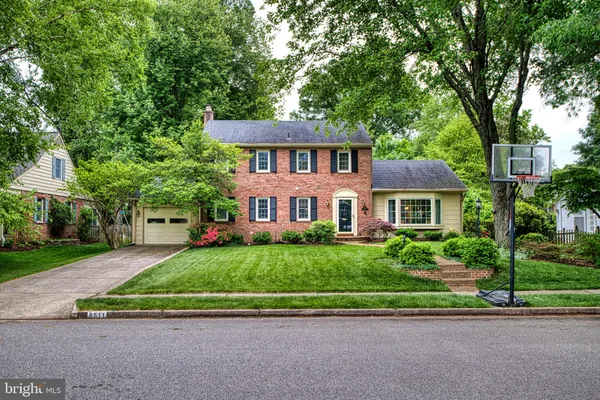 a view of house with a big yard and large trees