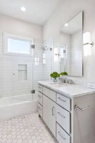 a bathroom with a granite countertop sink a toilet a mirror and bathtub
