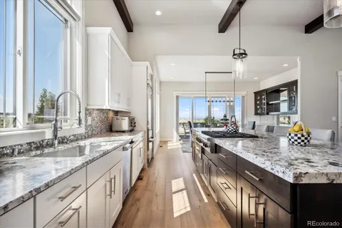 a view of a kitchen with stainless steel appliances granite countertop a sink stove and cabinets
