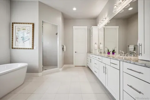 a large bathroom with a granite countertop sink a toilet a large mirror a shower and a bathtub