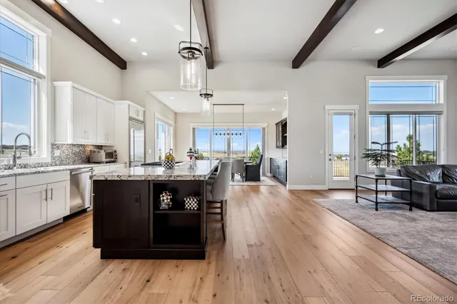 a kitchen with stainless steel appliances granite countertop a refrigerator a sink dishwasher a stove and white cabinets with wooden floor