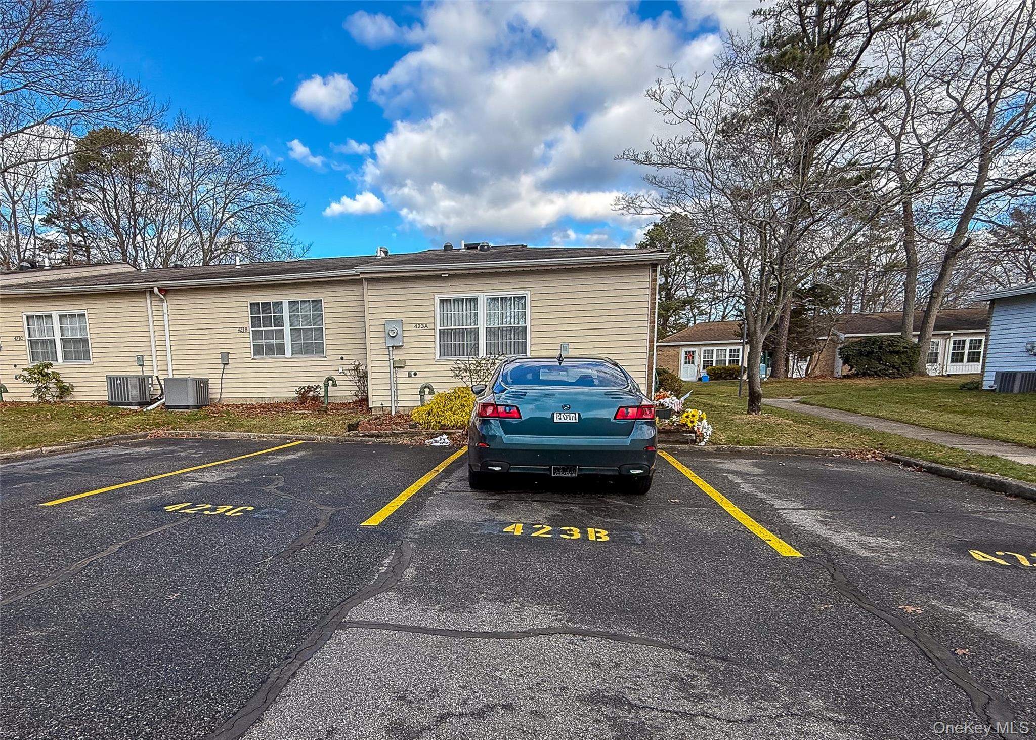 423 Woodbridge Drive, Unit B Ridge, NY 11961 - Photo 12 of 13 View of building exterior featuring uncovered parking