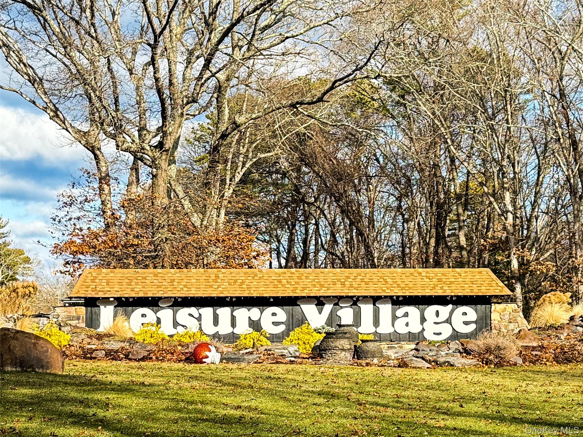 423 Woodbridge Drive, Unit B Ridge, NY 11961 - Photo 2 of 13 Community sign with a lawn
