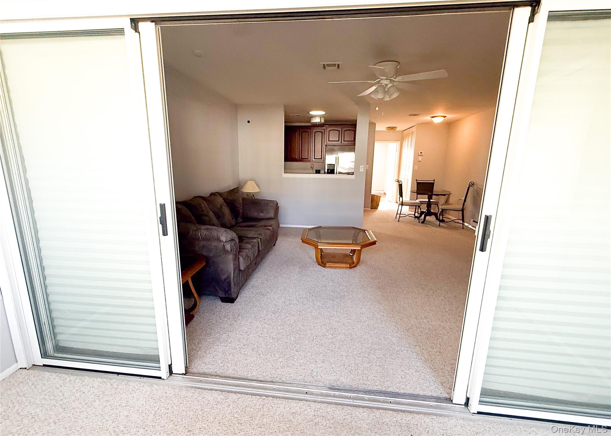 423 Woodbridge Drive, Unit B Ridge, NY 11961 - Photo 7 of 13 Living room with light carpet and a ceiling fan