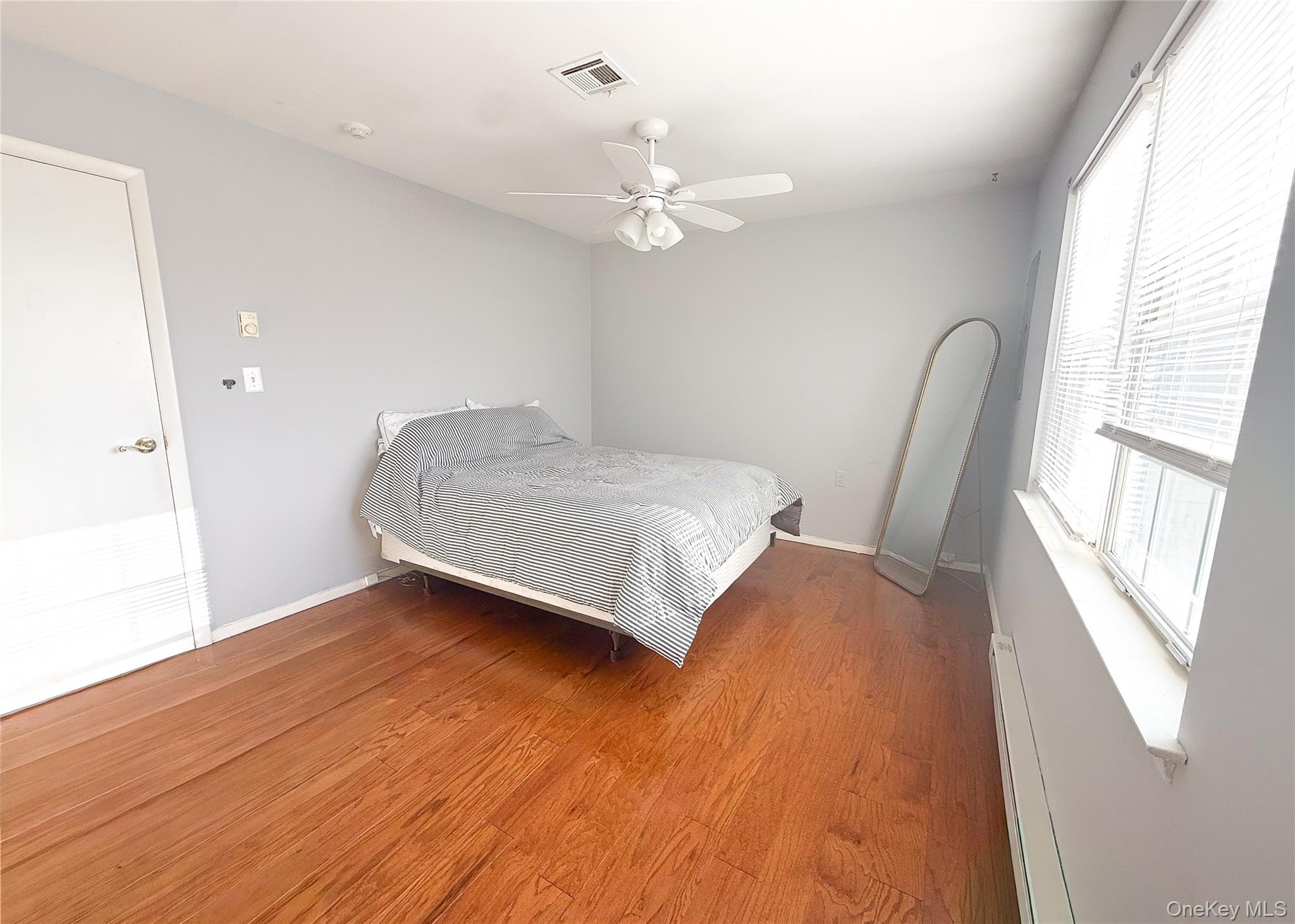 423 Woodbridge Drive, Unit B Ridge, NY 11961 - Photo 9 of 13 Bedroom with a baseboard radiator, wood finished floors, and a ceiling fan