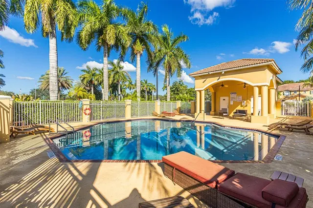 a view of a swimming pool with a lawn chairs under palm trees