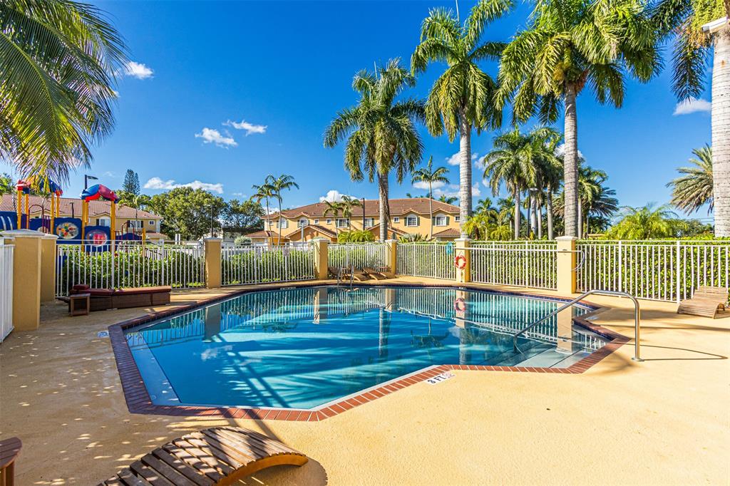 5545 Monte Carlo Place, Unit 5545 Margate, FL 33068 - Photo 38 of 41 a view of a swimming pool with a lawn chairs under palm trees