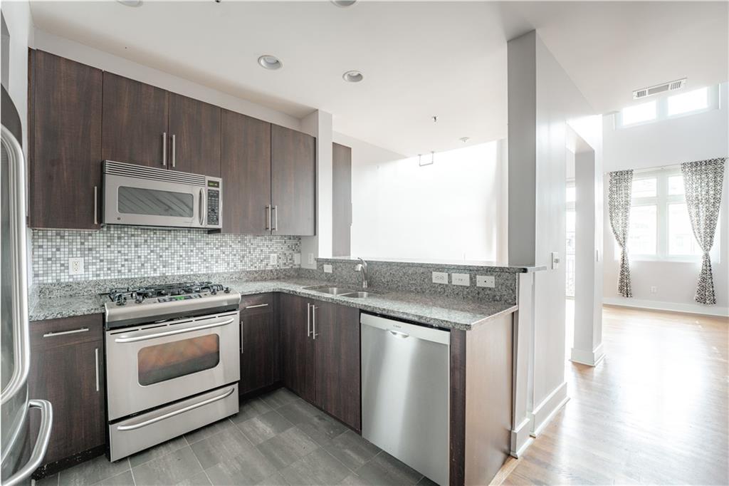 1221 Caroline Street Northeast, Unit 208 Atlanta, GA 30307 - Photo 11 of 26 a kitchen with stainless steel appliances granite countertop a stove and a microwave