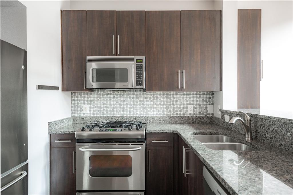 1221 Caroline Street Northeast, Unit 208 Atlanta, GA 30307 - Photo 12 of 26 a kitchen with granite countertop a stove top oven microwave and cabinets