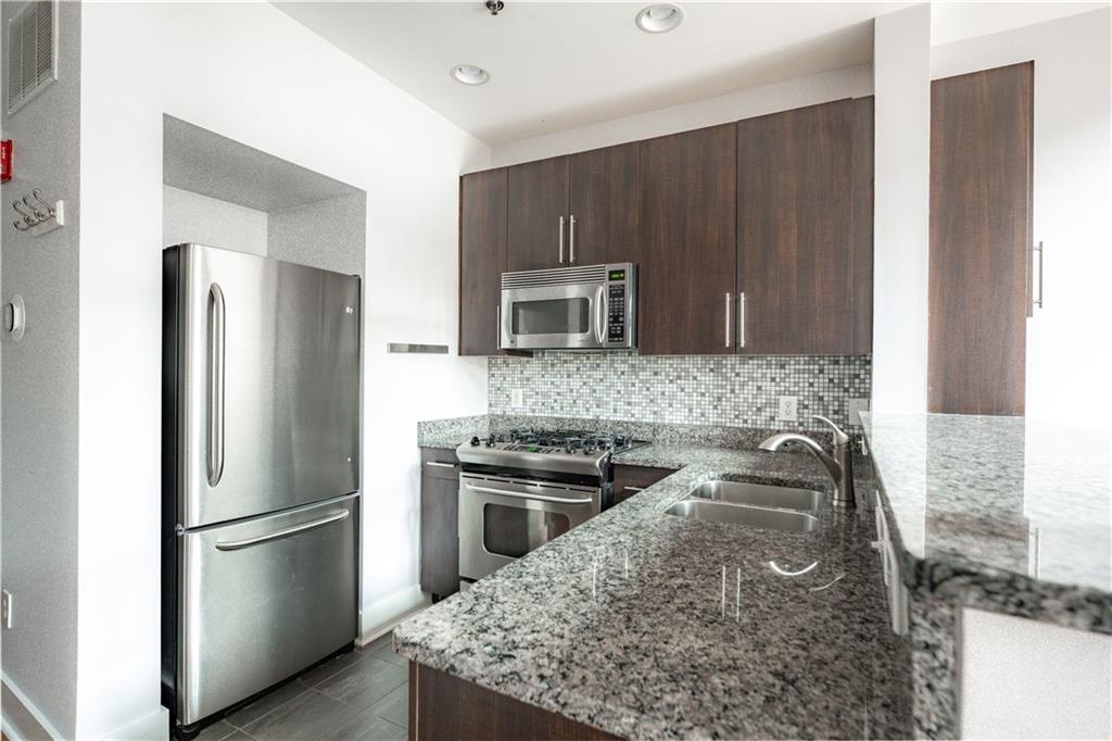 1221 Caroline Street Northeast, Unit 208 Atlanta, GA 30307 - Photo 10 of 26 a kitchen with stainless steel appliances granite countertop a refrigerator stove and microwave