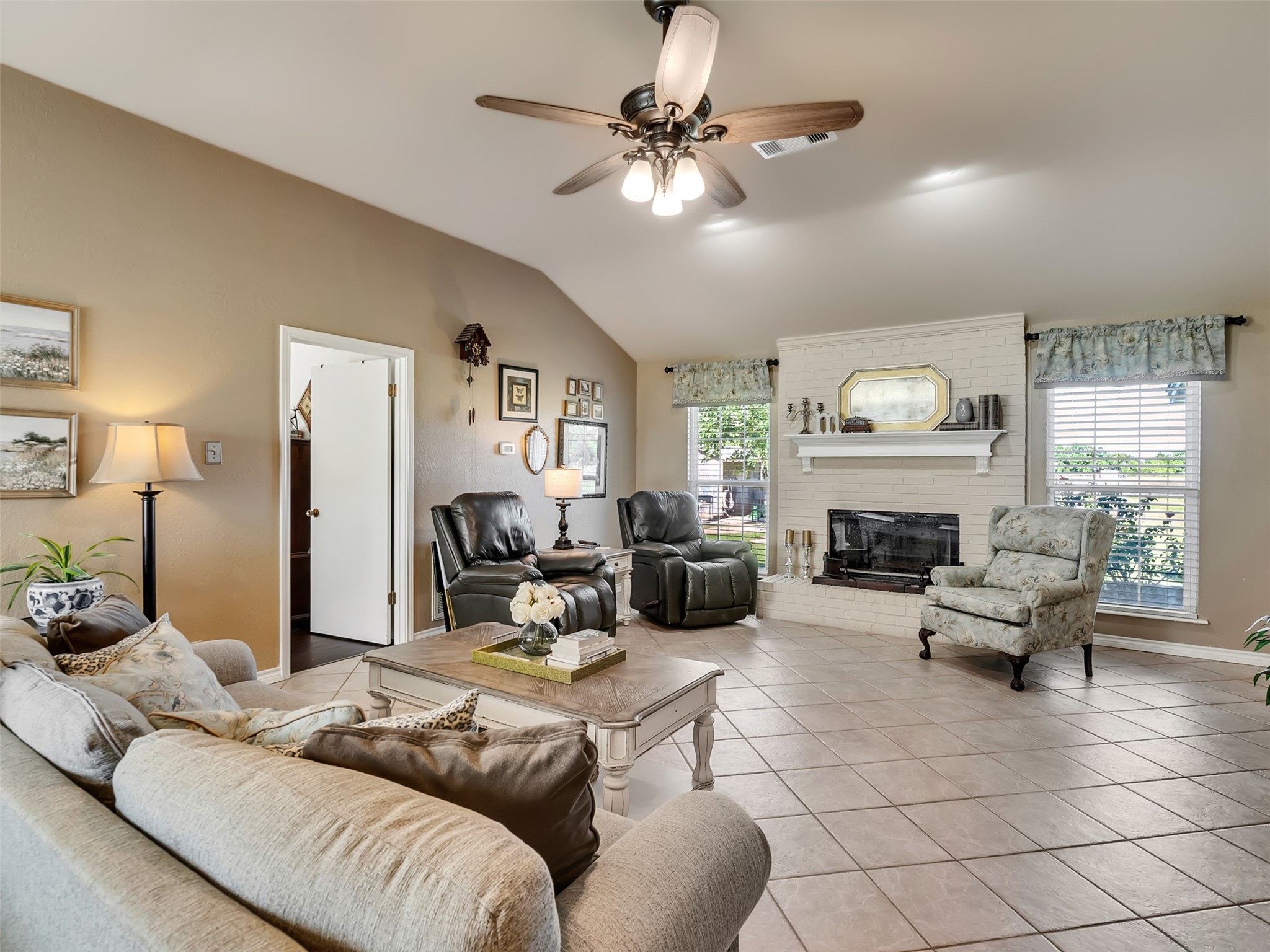 This spacious living room where soaring high ceilings create an open, airy feel, while a stunning wood-burning fireplace serves as the room's warm and inviting focal point.