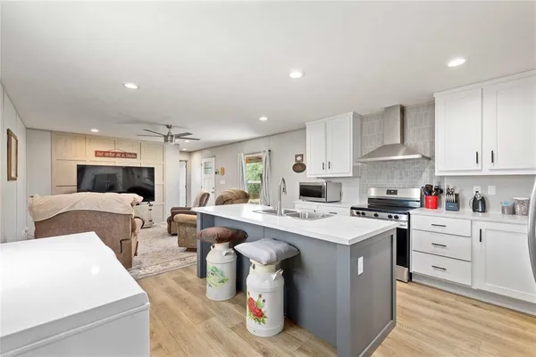 a kitchen with stainless steel appliances granite countertop a sink a stove a refrigerator and white cabinets with wooden floor
