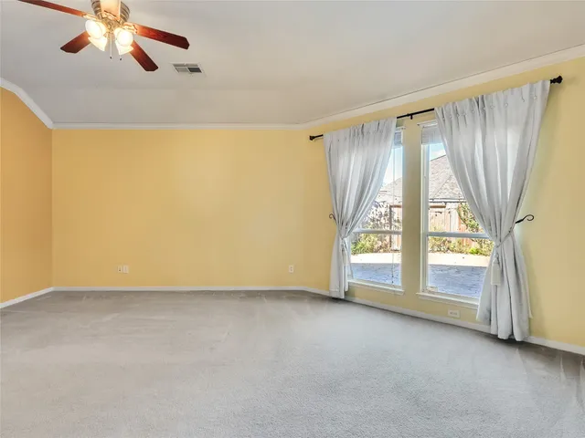 a view of an empty room with chandelier fan and fire place