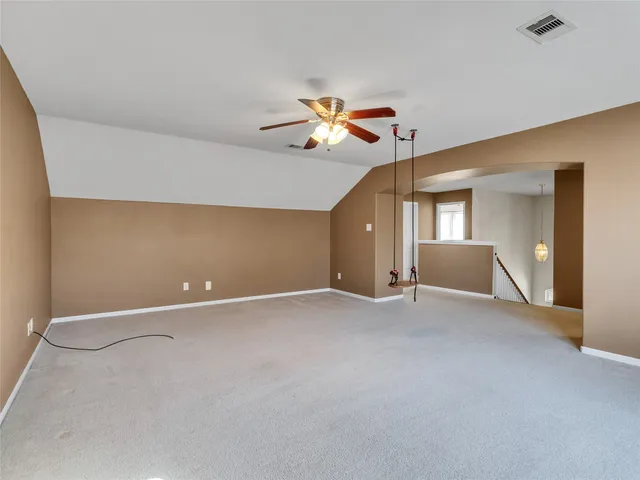 an empty room with chandelier fan and windows