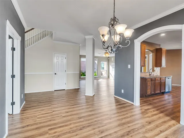 a view of a hallway with wooden floor and a chandelier