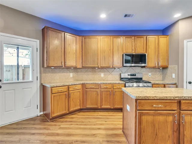 a kitchen with stainless steel appliances granite countertop a stove a sink and a microwave