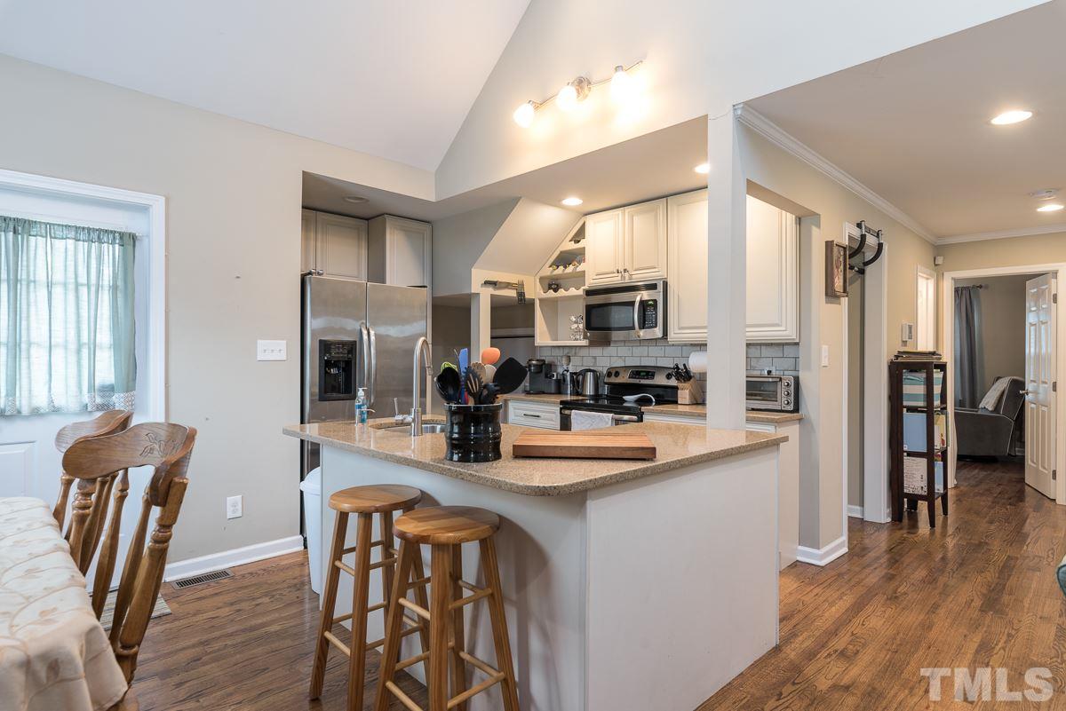 2212 Rumson Road Raleigh, NC 27610 - Photo 7 of 19 a kitchen with stainless steel appliances granite countertop dining table chairs and wooden floor