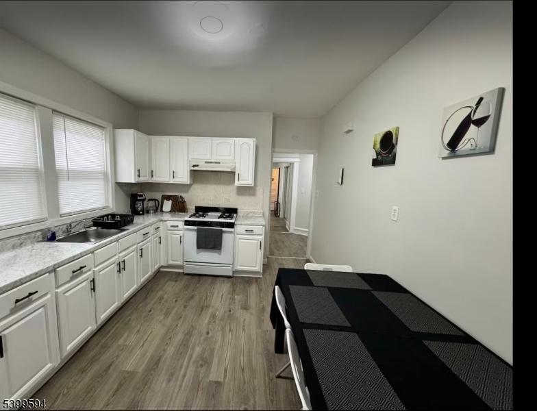 854 South 15th Street, Unit 2 Newark, NJ 07108 - Photo 4 of 9 a large kitchen with a refrigerator a sink dishwasher a stove and white cabinets with wooden floor