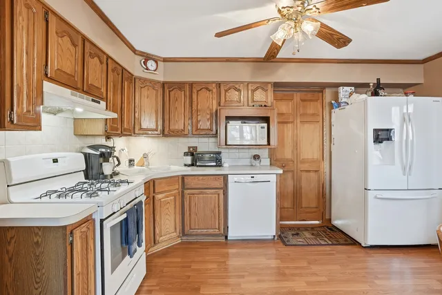 a kitchen with stainless steel appliances granite countertop a refrigerator a stove a sink and white cabinets with wooden floor