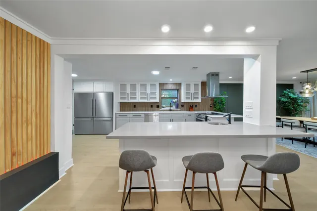 a kitchen with stainless steel appliances kitchen island granite countertop a refrigerator oven stove a oven and white cabinets