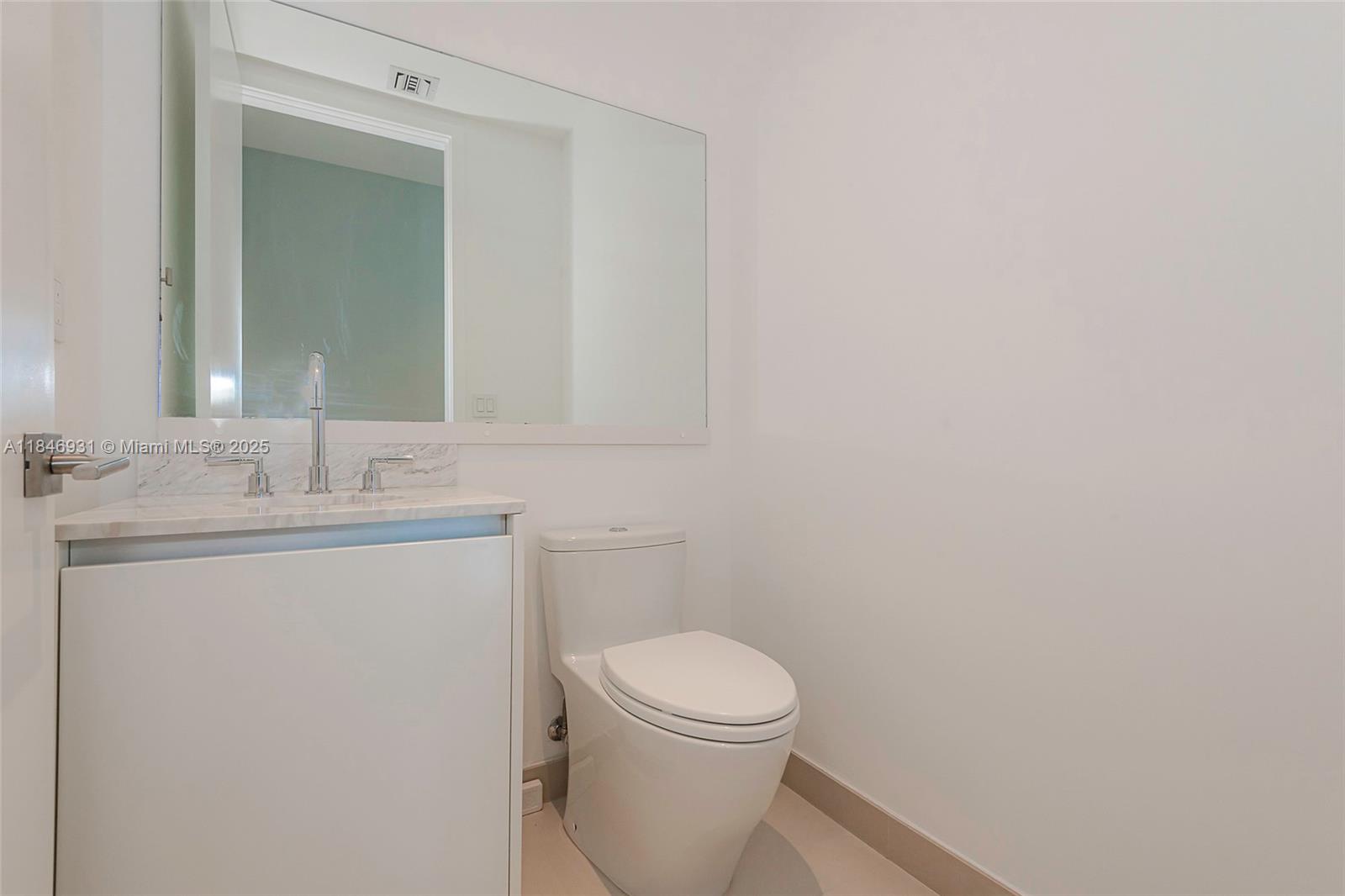 2821 South Bayshore Drive, Unit 7B Coconut Grove, FL 33133 - Photo 14 of 35 a bathroom with a toilet a sink and mirror