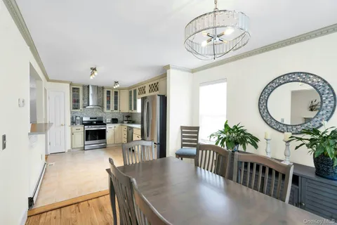 a kitchen with stainless steel appliances granite countertop a refrigerator a stove a sink dishwasher a dining table and chairs with wooden floor