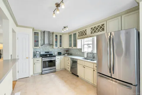 a kitchen with stainless steel appliances granite countertop a refrigerator a sink dishwasher a stove with white cabinets