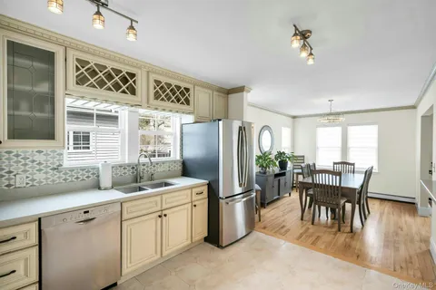 a kitchen with stainless steel appliances granite countertop a stove a refrigerator a dining table and chairs with wooden floor