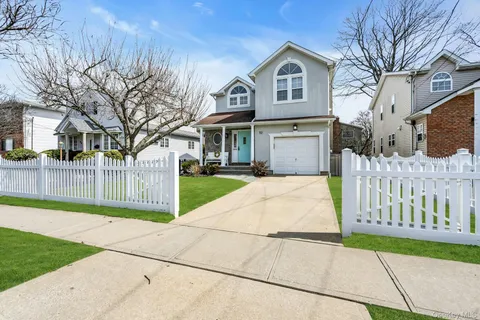 a view of a brick house with a big yard and large trees