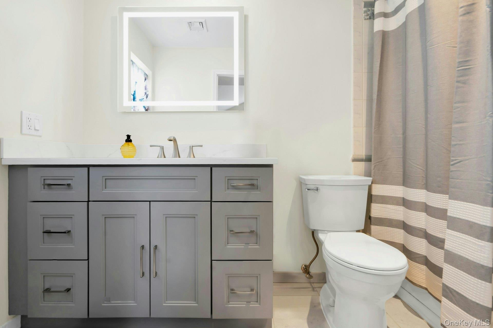 52 Edgewood Road Port Washington, NY 11050 - Photo 25 of 29 a bathroom with a toilet a sink a vanity and mirror