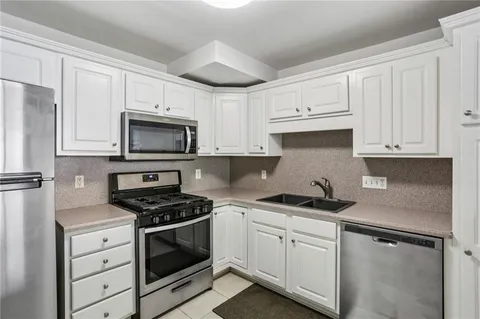 a kitchen with white cabinets stainless steel appliances and sink