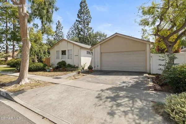 a view of a house with a yard and large tree