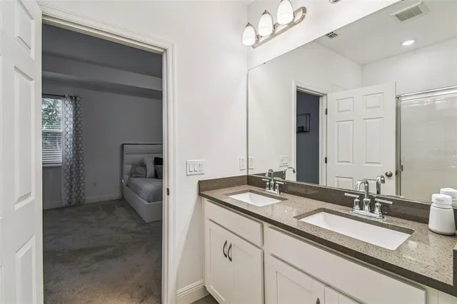 a spacious bathroom with a granite countertop sink a mirror and shower