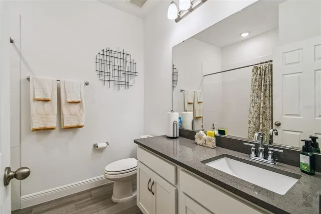 a bathroom with a granite countertop sink a toilet and a mirror