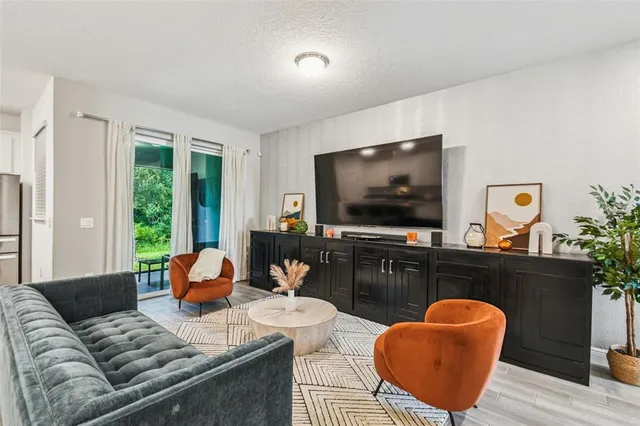 a living room with furniture a flat screen tv and a large window