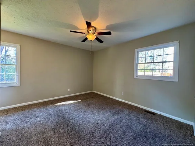 an empty room with windows and fan