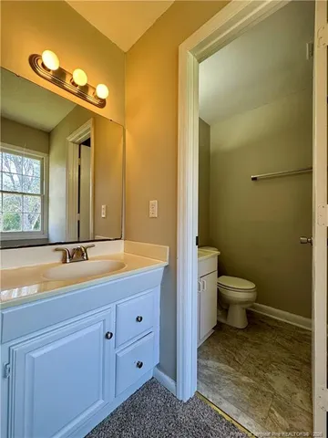 a bathroom with a granite countertop sink mirror vanity and toilet