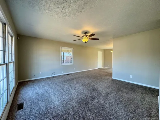 an empty room with a chandelier fan and windows