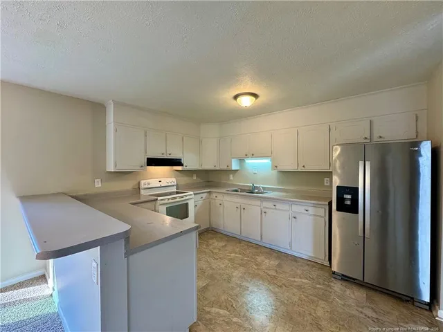 a kitchen with granite countertop a refrigerator stove top oven and sink