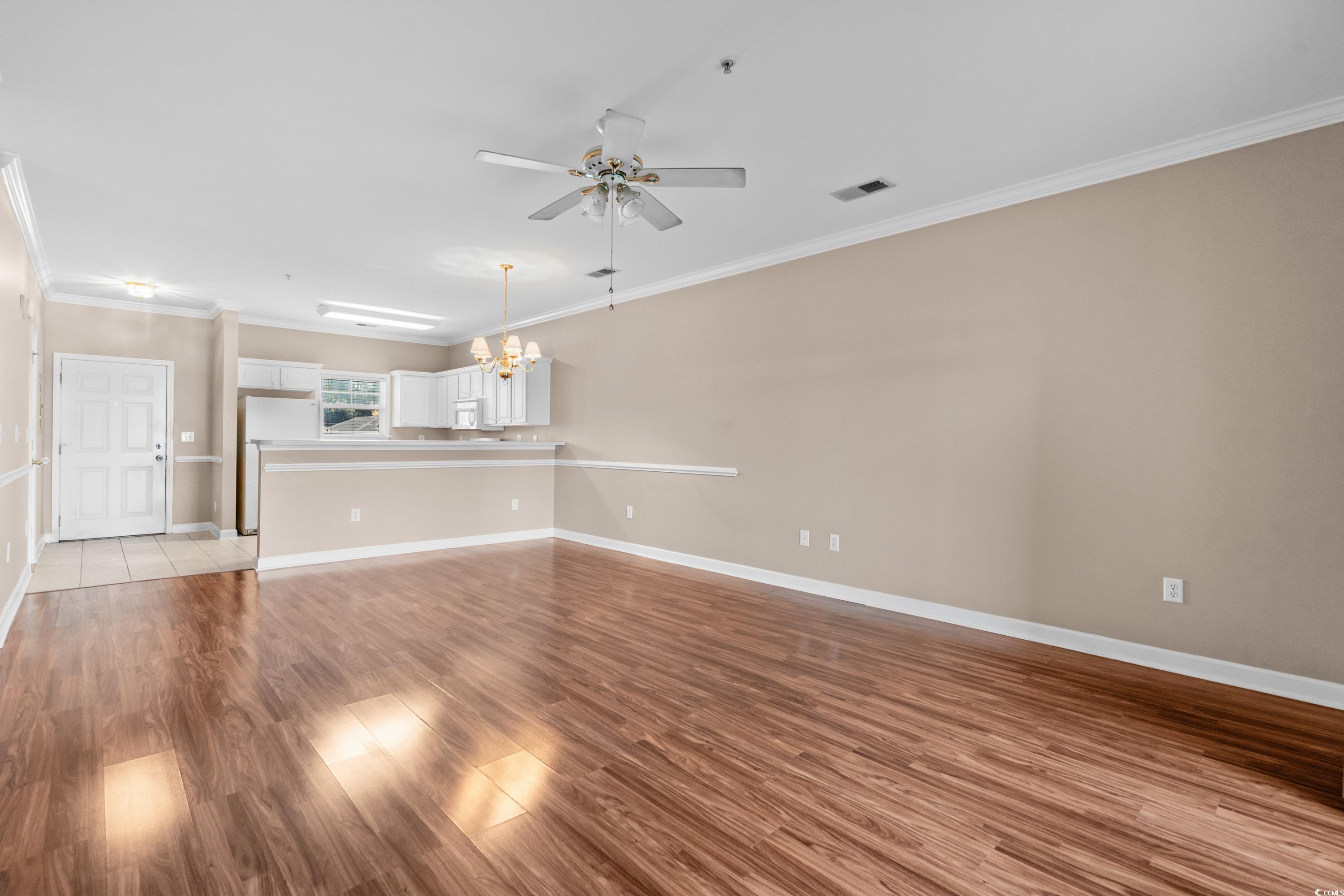 336 Kiskadee Loop, Unit B Conway, SC 29526 - Photo 11 of 40 Unfurnished living room with crown molding, light hardwood / wood-style flooring, and ceiling fan with notable chandelier