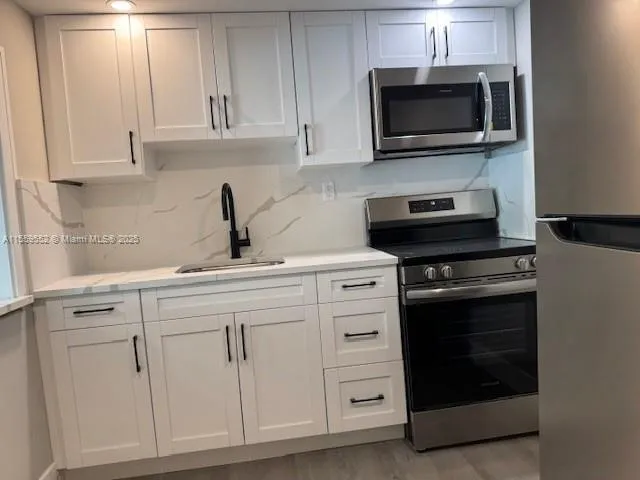 a kitchen with white cabinets and stainless steel appliances