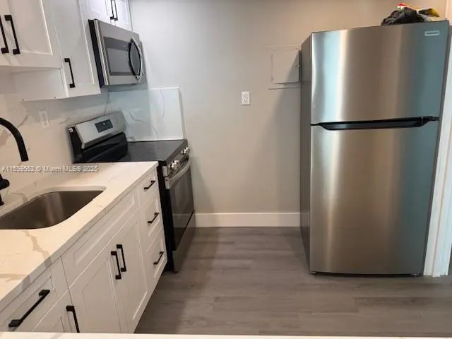 a kitchen with stainless steel appliances granite countertop a refrigerator a stove a sink and a microwave