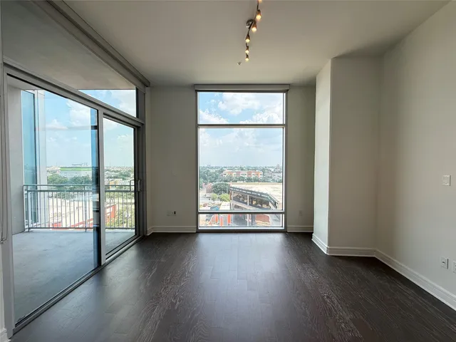 an empty room with wooden floor and windows with curtains