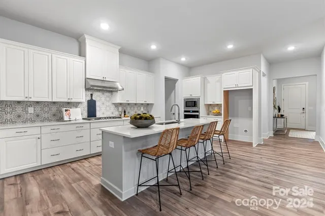 a kitchen with stainless steel appliances kitchen island granite countertop a table chairs sink refrigerator and cabinets