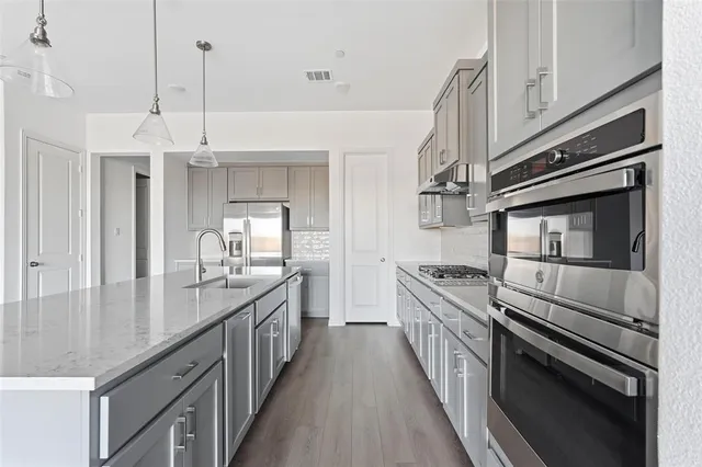a kitchen with stainless steel appliances granite countertop a sink a stove and a wooden floors