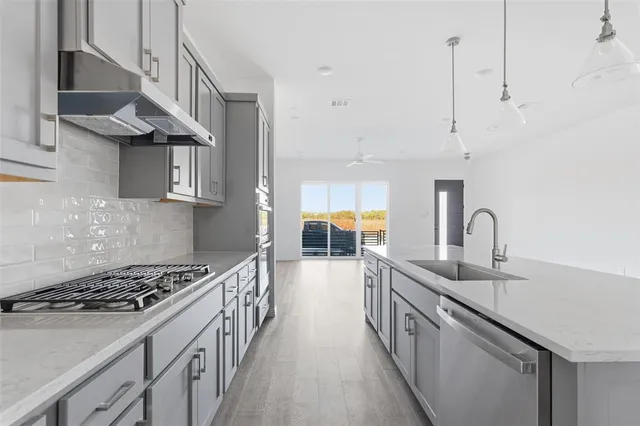 a kitchen with stainless steel appliances granite countertop a sink stove and refrigerator